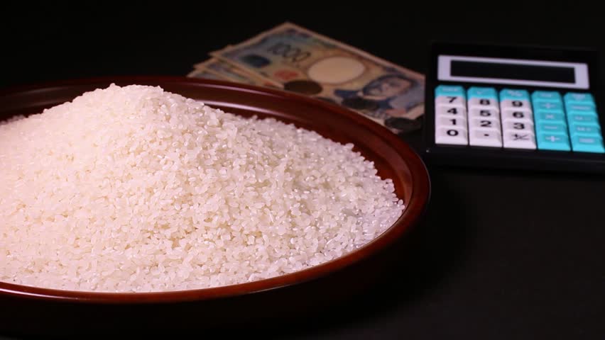 Rice on a tray, money and a calculator - rotating. The currency is Japanese 1000 yen notes and coins.