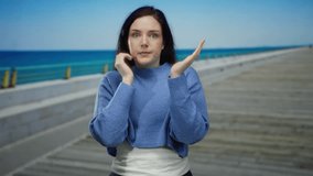 Woman on promenade with brunette hair gazing at the beach wearing a blue sweater, creating a serene and contemplative atmosphere against the vast ocean shoreline backdrop. - Powered by Shutterstock - Get 15% off with code: PIKWIZARD15