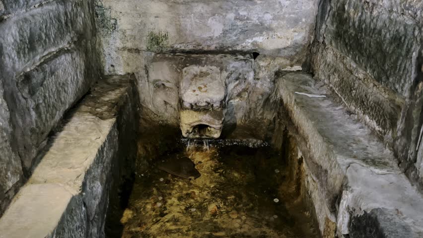 An ancient stone-carved spring spout, which tourists treat as a wish-making pond by throwing coins into it.