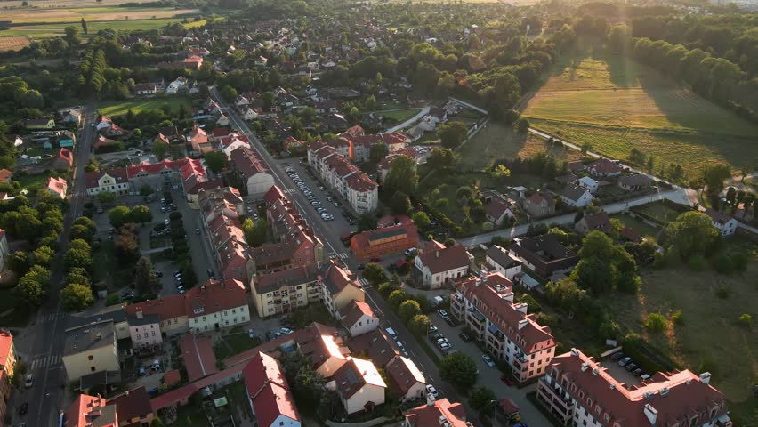 Aerial view of small European town with streets and green trees at sunset. Bird eye view of village in Poland. Landscape with residential buildings in suburban neighborhood