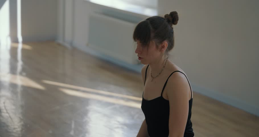 Flexible girl in the splits and performs graceful flexible movements lying on the floor during her contemporary parter dance in the choreography studio