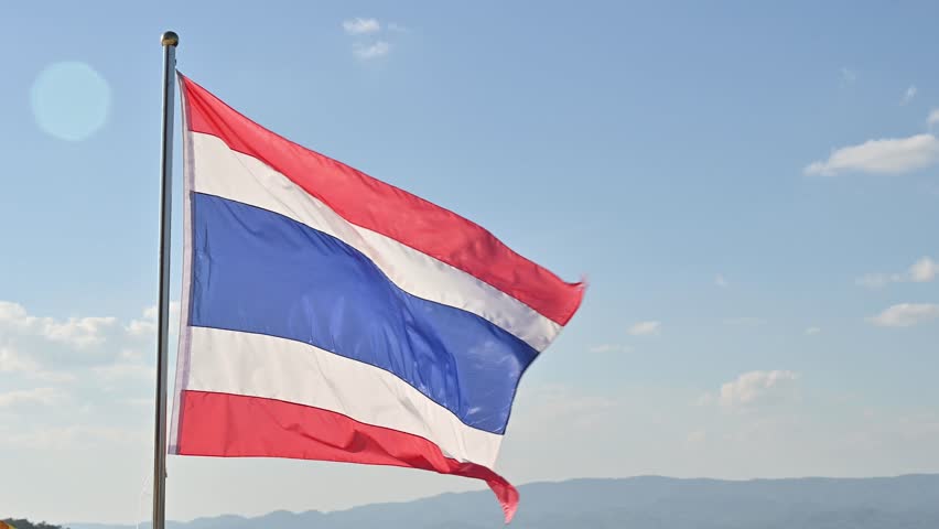 A Thailand national flag blowing by wind against blue sky.