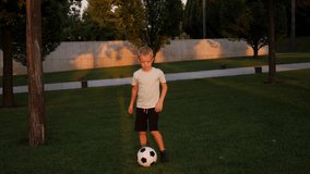 An eight-year-old boy in sports clothes is engaged with a soccer ball in a city park in the summer at sunset. The child is engaged in football. - Powered by Shutterstock - Get 15% off with code: PIKWIZARD15