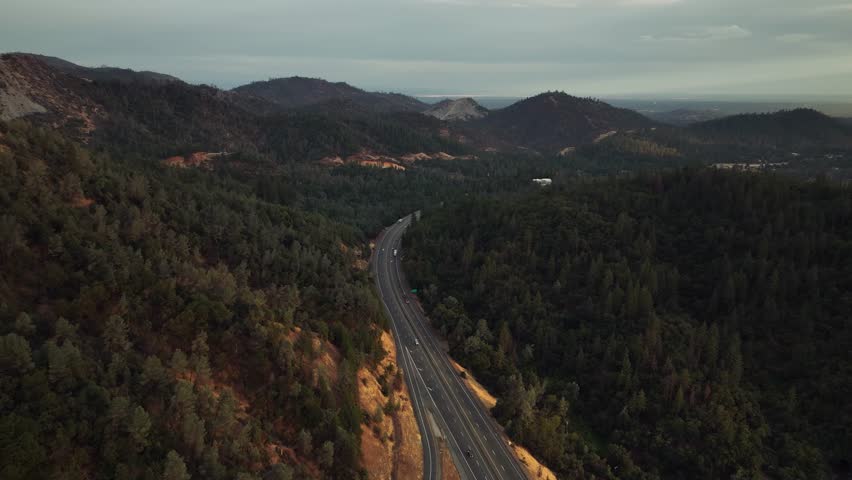 Aerial drone view of California mountains with lake, road and sunset