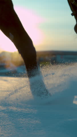 SLOW MOTION TIME WARP, CLOSE UP, LENS FLARE, DOF: Detail of dark horse walking trough deep snow blanket at winter sunset. Golden winter morning sunrays shine on stallion's legs walking in fresh snow.