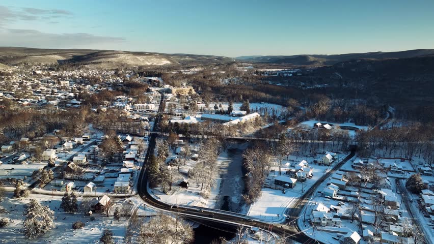 Aerial drone view of snowy town and river in Pennsylvania, USA, winter landscape