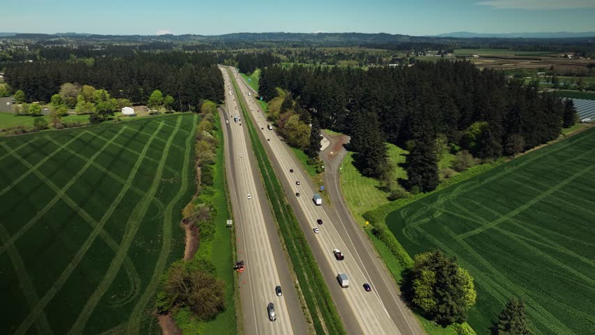 Aerial drone view of highway with trucks, rest area, fields and forest in Oregon, USA