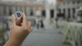 Man holding bitcoin against blurred background of vatican city at san pedro square, highlighting cryptocurrency in iconic outdoor urban setting with caucasian male hand focus. - Powered by Shutterstock - Get 15% off with code: PIKWIZARD15