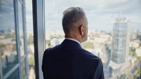Rich director standing window business center closeup. Serious senior businessman looking beautiful cityscape in modern office. Confident gray-hair man professional in elegant suit pondering career. - Powered by Shutterstock - Get 15% off with code: PIKWIZARD15