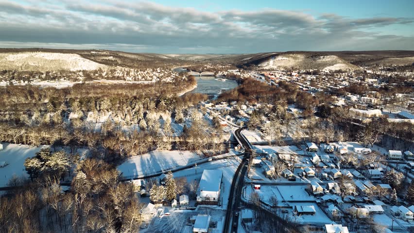 Aerial drone view of snowy town and river in Pennsylvania, USA, winter landscape