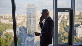 Senior businessman conflicting by smartphone in office high-rise building. Stressed aged leader shouting cellphone standing by panoramic window. Furious executive feel stress after business phone call - Powered by Shutterstock - Get 15% off with code: PIKWIZARD15