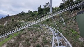 Mountain roller coaster track winding through scenic hillside with greenery. - Powered by Shutterstock - Get 15% off with code: PIKWIZARD15