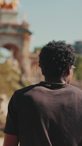 Vertical video, A young man admires the architecture in Ciutadella Park, Barcelona, Spain. He
