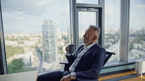Successful entrepreneur holding cup coffee sitting comfortable office chair. Relaxed senior businessman sipping beverage looking panoramic window. Elegant manager making work break enjoying cityscape. - Powered by Shutterstock - Get 15% off with code: PIKWIZARD15