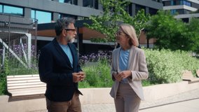 Angry businessman and calm businesswoman arguing outdoors in business district. Man frustrated, woman indifferent, tense dispute in professional urban environment - Powered by Shutterstock - Get 15% off with code: PIKWIZARD15