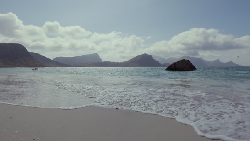Scenic beach with mountainous backdrop in Lofoten, Norway under cloudy skies