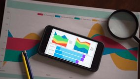 Smartphone with colorful graphs and financial analytics on desk, symbolizing digital finance and mobile data visualization. - Powered by Shutterstock - Get 15% off with code: PIKWIZARD15