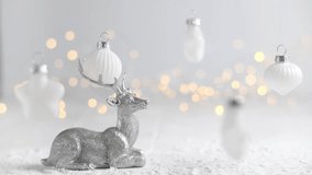 Silver reindeer figurine resting on snow-covered surface, surrounded by white christmas ornaments hanging amidst a backdrop of warm fairy lights, creating a magical and festive holiday atmosphere - Powered by Shutterstock - Get 15% off with code: PIKWIZARD15