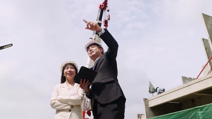 Male engineer supervising construction site and businesswoman owns project stand watching precast concrete panels are lifted crane assembled into residential houses.
 - Powered by Shutterstock - Get 15% off with code: PIKWIZARD15