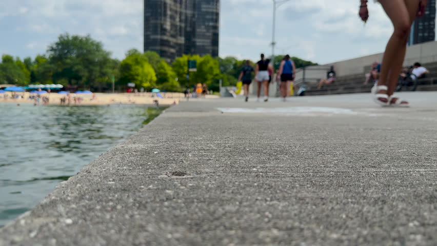 Summer scene on the Lakefront Trail in Chicago, Illinois, USA. Tourists and locals enjoy a beautiful Summer day on Lake Michigan. Ohio Street Beach can be seen in the distance.