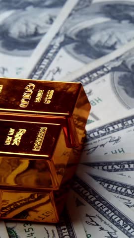 Vertical Video Captures Shiny Gold Ingots Spinning Over Cash,Reflecting Wealth, Luxury, And Smart Financial Investment Strategy.Slow Rotation Gold Bars Hundred Dollar Bill Vertical Format Representing
