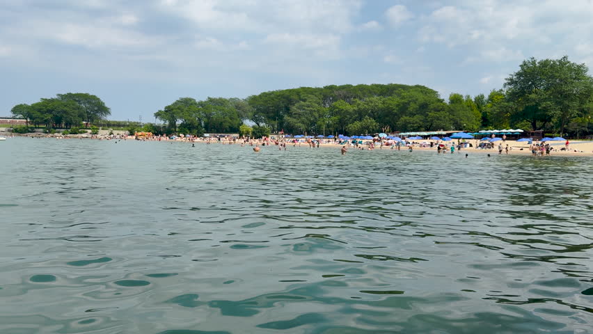 Tourists and locals cool off at the beach on Lake Michigan in Chicago, Illinois. Summer scene on a hot July day in the city. Located at the Ohio Street Beach.