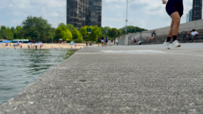 Summer scene on the Lakefront Trail in Chicago, Illinois, USA. Tourists and locals enjoy a beautiful Summer day on Lake Michigan. Ohio Street Beach can be seen in the distance.