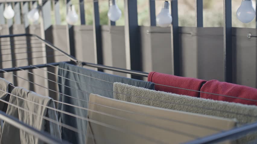 Freshly washed towels and clothes drying on outdoor rack in sunlight. Concept of eco friendly lifestyle and household routine