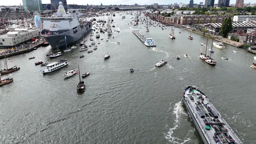Drone footage of Sail Amsterdam 2025 - Sailing Parade in Amsterdam, Netherlands held in August 2025. Enjoy the view of the sail boats by the docks and in the canals of Amsterdam from a Birds Eye view