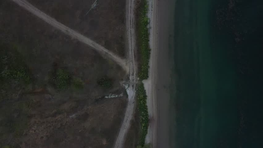 Reverse Top-down drone view of Stanley Lake rippling water and shore