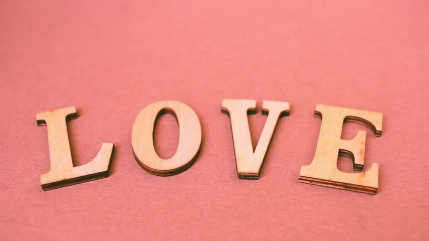Creative concept of a hand arranging alphabet letters to form the word “LOVE.” Perfect for Valentine’s Day, weddings, romantic greetings, posters, social media posts, and typography designs.