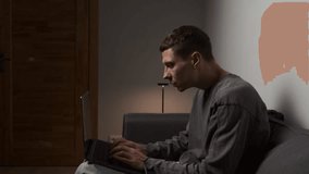 Incorrect posture while working on laptop. Young man sitting hunched on sofa using laptop with poor ergonomics, harmful effect on spine and posture in authentic modern living room - Powered by Shutterstock - Get 15% off with code: PIKWIZARD15