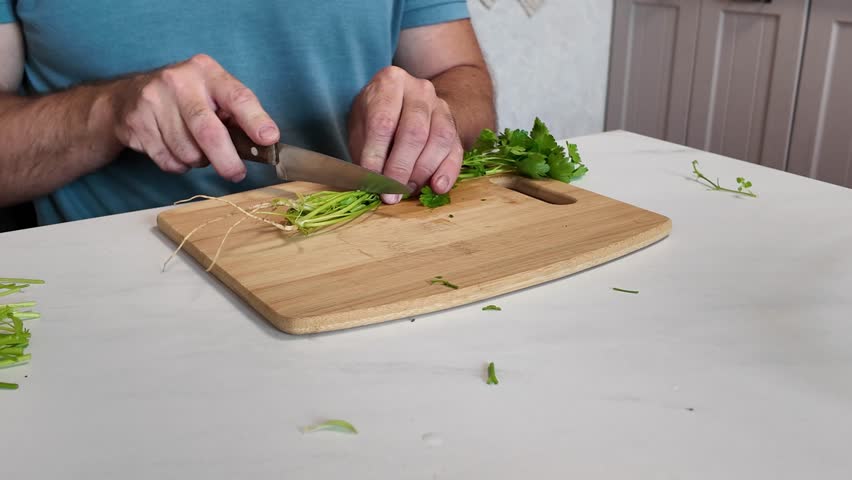 the cook's hands finely chop the parsley. cooking green vegetables, vegetarian food.