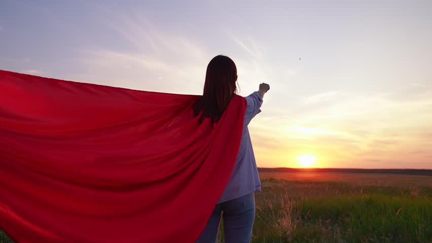 Beautiful superhero woman dream in nature. Teen girl playing in red cape in park sunset. Girl fantasy in red cape in park. Red superheroine costume. Superhero girl carnival at sunset. Fly imagination