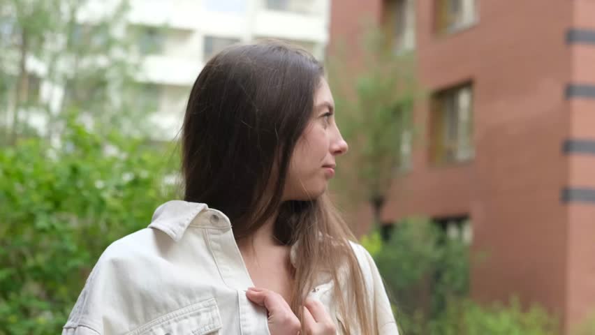 Cute cheerful charming girl poses for camera in summer on city street, hands and fingers showing V sign