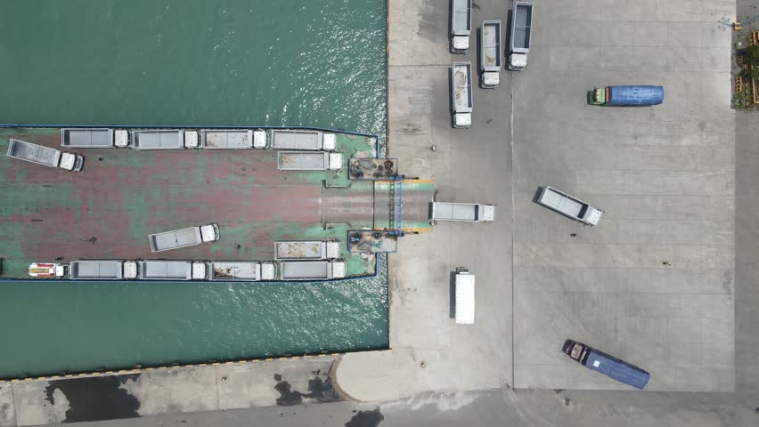 top down view truck loading into a car carrier ship. Car ferry leaving docks fully loaded.