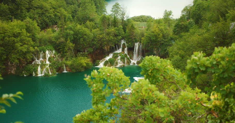Cascading waterfalls flow into a tranquil emerald lake in Plitvice park Croatia