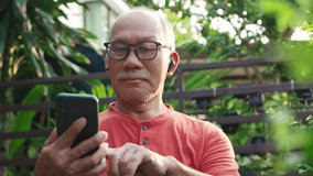 Senior Asian Man Using Smartphone and earphones in Garden, Engaged and Happy with Technology Outdoors - Powered by Shutterstock - Get 15% off with code: PIKWIZARD15