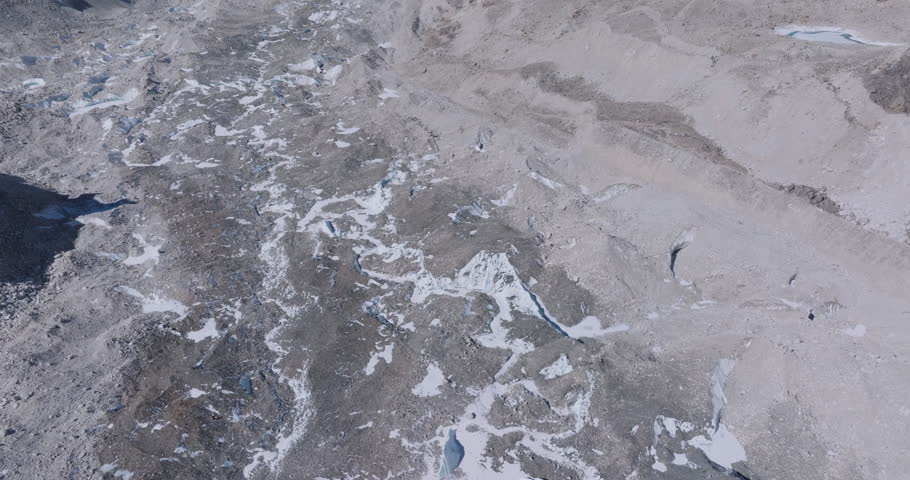 Top-down drone view of Everest Base Camp and Khumbu Glacier in Nepal with melting snow, high-altitude tents, Sagarmatha peaks, and layered Himalayan mountain ranges under a clear blue sky