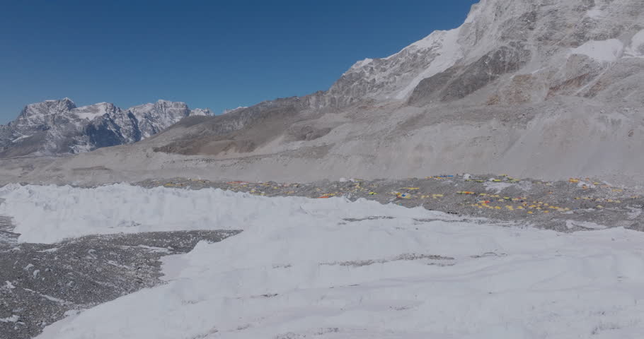 Landscape of Everest Base Camp and Khumbu Glacier in Nepal, Drone showing melting snow, sandy dry land, base camp tents, and Sagarmatha’s majestic peaks under a clear blue sky tourism experience