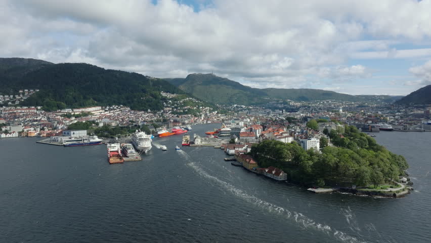 Aerial approach toward Bergen city center, showcasing the waterfront, mountains and traditional architecture