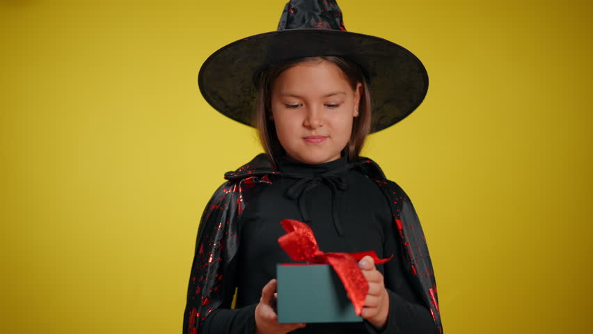 A young witch joyfully unwraps a beautifully colorful gift, showcasing the true Halloween spirit and her curiosity