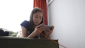 young girl playing on smartphone with headphones, concept of online gaming, youth media, digital childhood - Powered by Shutterstock - Get 15% off with code: PIKWIZARD15