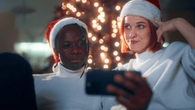 Happy multiethnic spouses celebrating Christmas, calling by video to friends. Portrait of african american husband and caucasian wife in Santa hats on head, modern technology for communication online - Powered by Shutterstock - Get 15% off with code: PIKWIZARD15