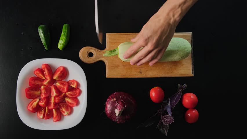 Cutting Zucchini on Black Table. Fast Motion Cooking Preparation with Fresh Vegetables and Herbs, Top View Shot for Healthy Lifestyle Video