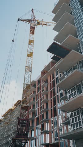 the process of building an apartment building with large construction cranes	