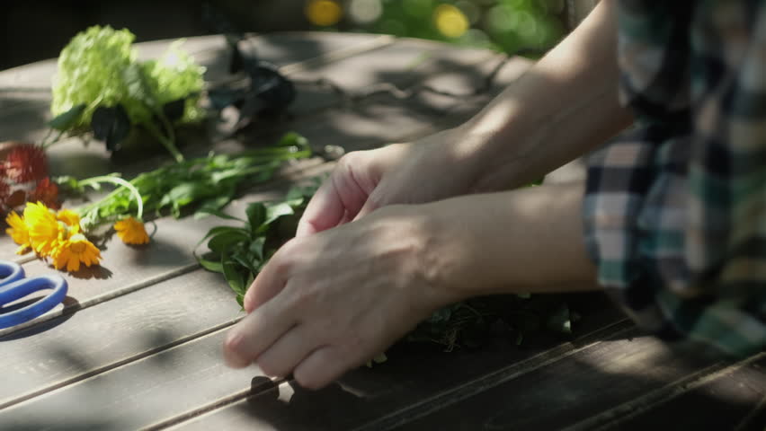 DIY seasonal summer home decor. Hands making floral wreath outdoors