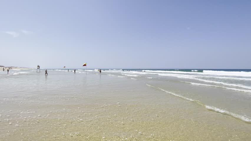 Panning along the shore of Mimizan-Plage, France, to a sign prohibiting swimming