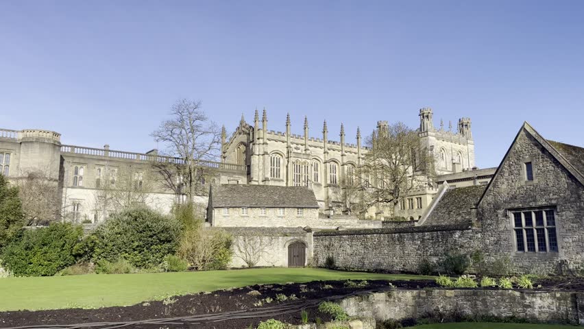 Historic view of Christ Church in Oxford with stone buildings, medieval architecture, and a well-kept garden in the foreground.