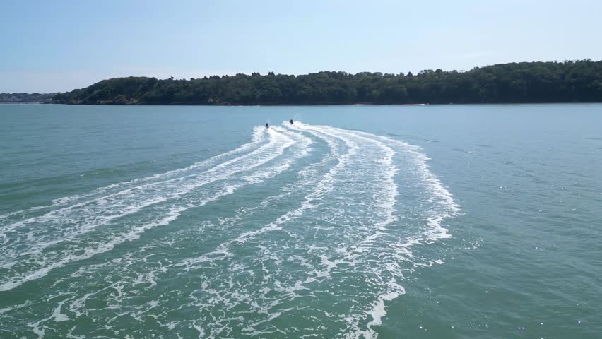 Torbay, South Devon, England: DRONE VIEWS: The drone follows two jet skiers heading across the bay towards Brixham. Torbay is a popular UK holiday resort for water sports enthusiasts.